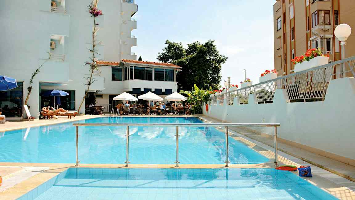 En bild av ett hotell med pool, sittgrupp med parasoller och solstolar. (AI-genererad text)