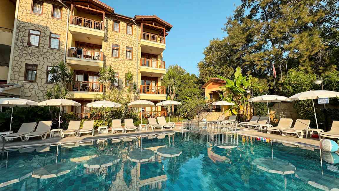 Bild av hotellfasad med pool och solstolar framför. (AI-genererad text)