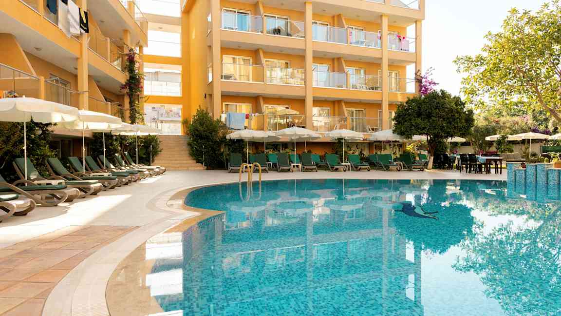 Byggnad med balkonger och en pool i förgrunden. (AI-genererad text)