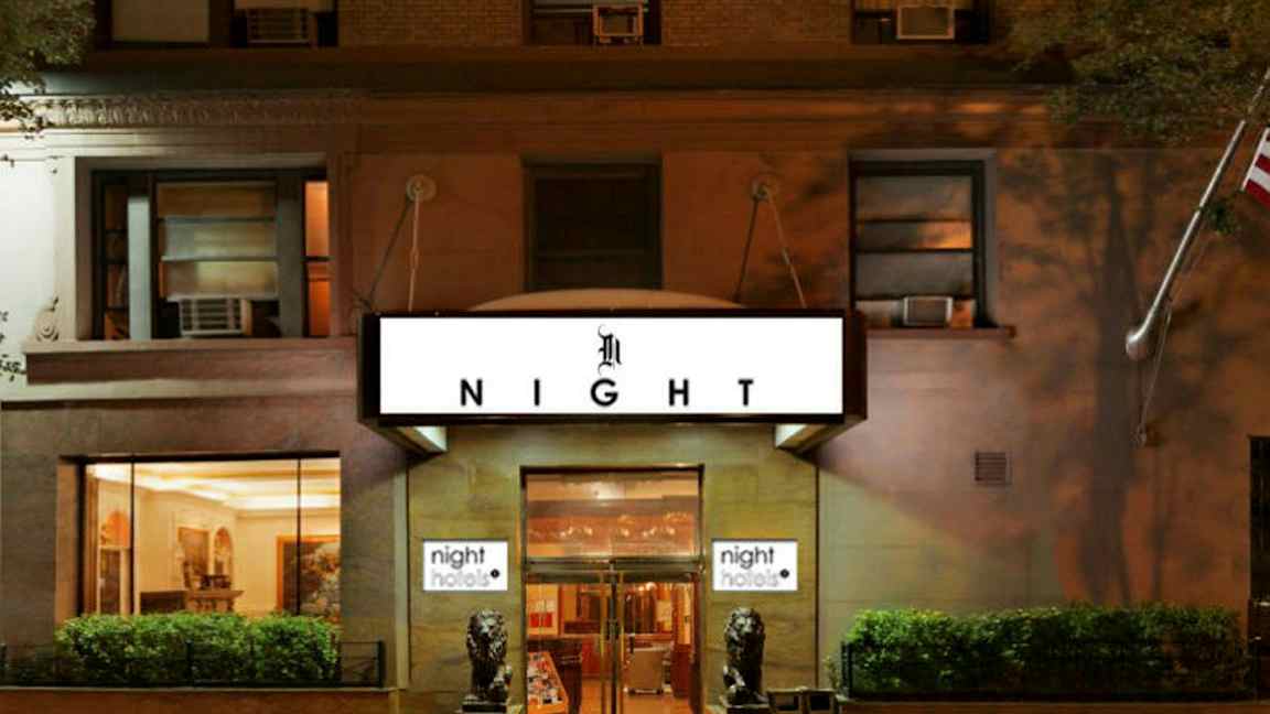 Hotellfasad med skylt som visar texten 'NIGHT', två dekorerade lejonstatyer utanför entrén. (AI-genererad text)