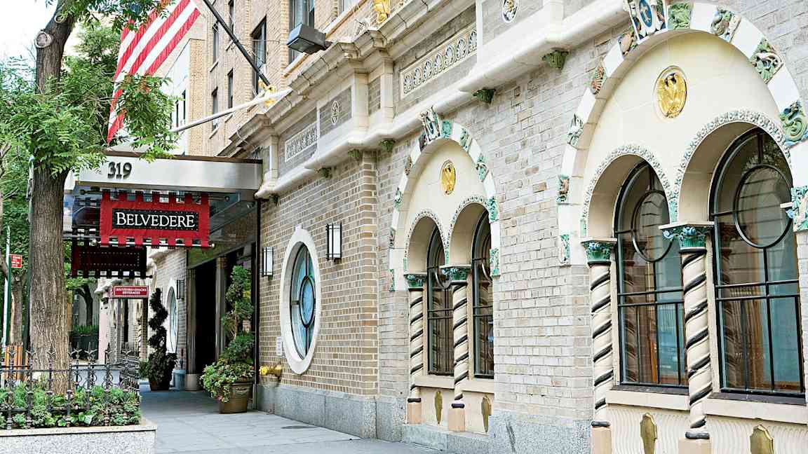 Fasaden av en byggnad med utsmyckade fönster och en ingång med en röd skylt som säger 'Belvedere'. (AI-genererad text)