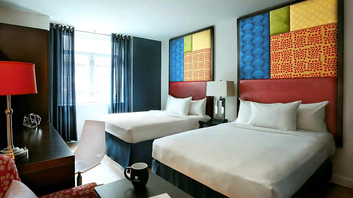 Hotellrum med två sängar, moderna möbler och dekorativa element. (AI-genererad text)