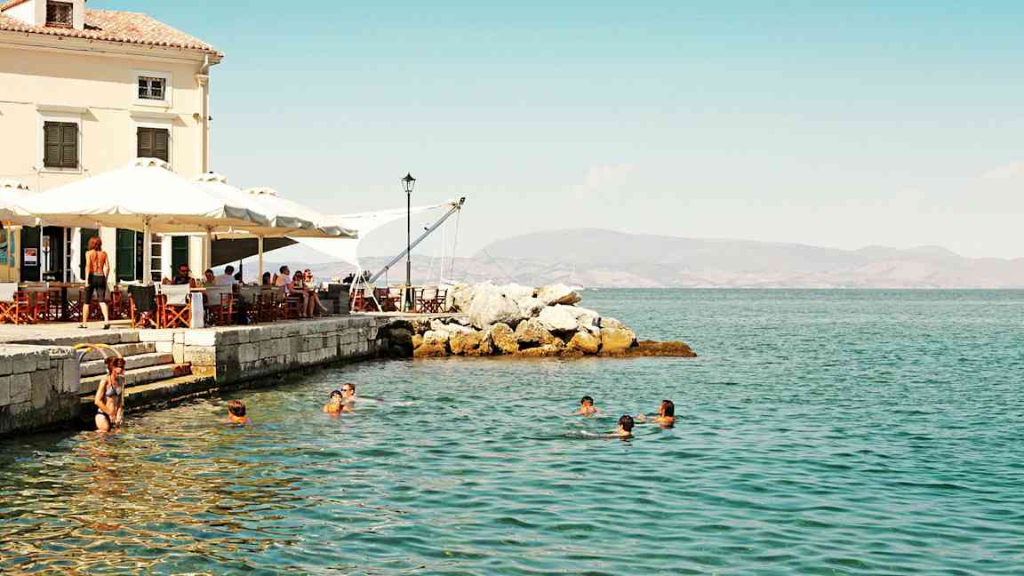 Personer simmar i havet nära ett café vid stranden. (AI-genererad text)