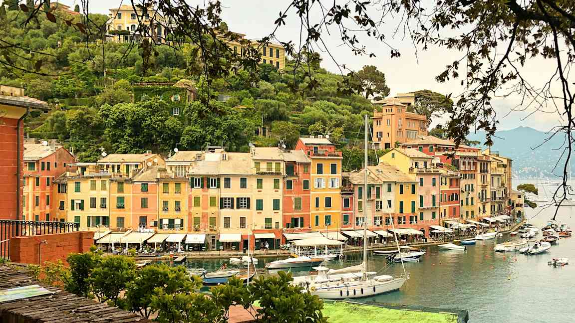 En hamn med färgglada byggnader och segelbåtar vid vattnet. (AI-genererad text)