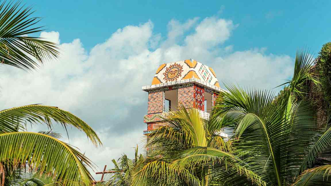 Dekorerad tornbyggnad synlig bakom palmer. (AI-genererad text)