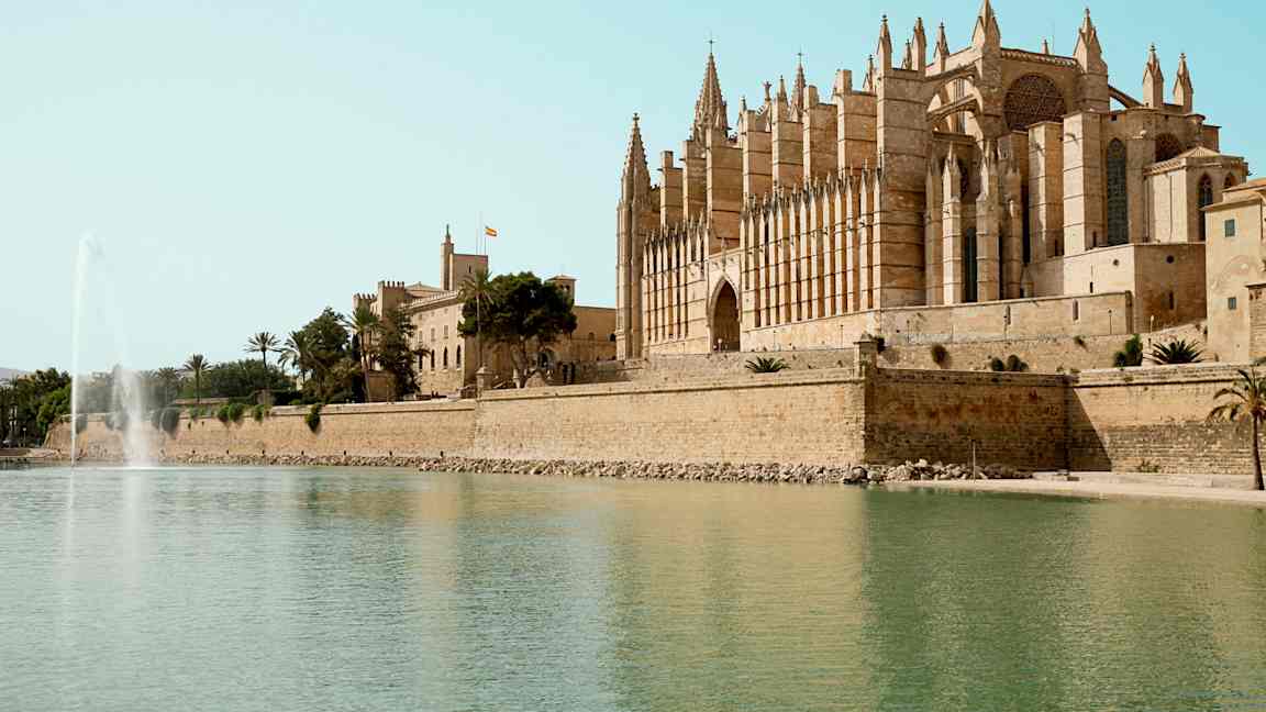 En katedral vid vattnet med en fontän i förgrunden. (AI-genererad text)