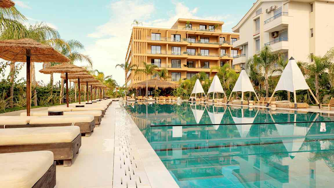 Utomhuspool med solstolar och parasoller vid ett hotell. (AI-genererad text)