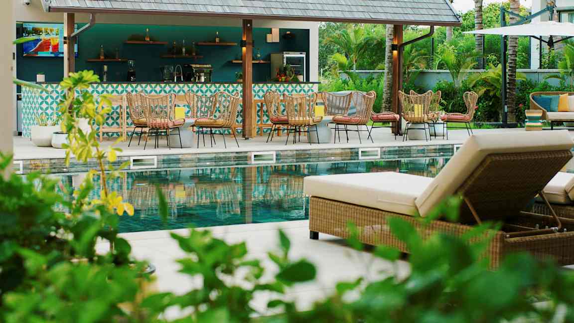 Bild av en poolområde med solstolar och en bar i bakgrunden. (AI-genererad text)