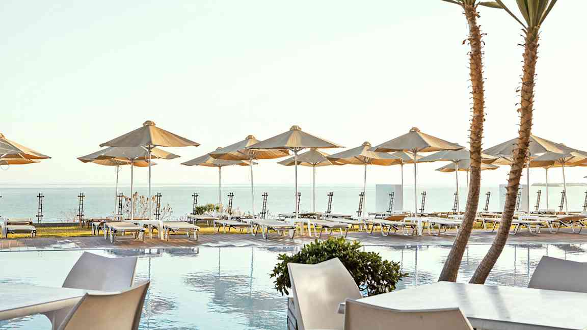 Soldäck vid pool med solstolar och parasoller vid havet. (AI-genererad text)