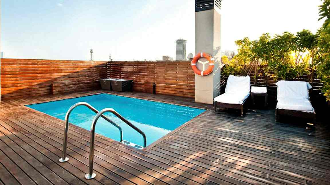 En takterrass med en liten pool, omgiven av ett trädäck och solstolar. (AI-genererad text)