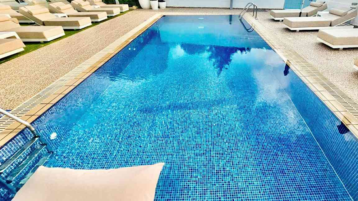 Utomhuspool omgiven av solstolar och parasoller. (AI-genererad text)