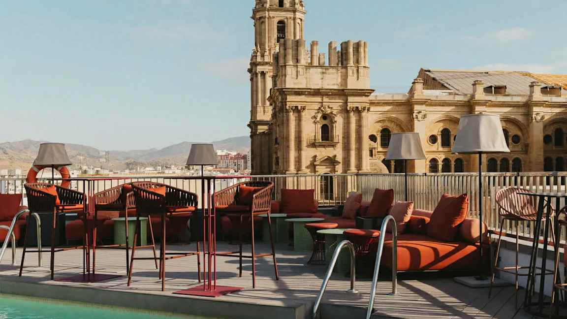 En takterrass med pool och loungemöbler, med en historisk byggnad i bakgrunden. (AI-genererad text)