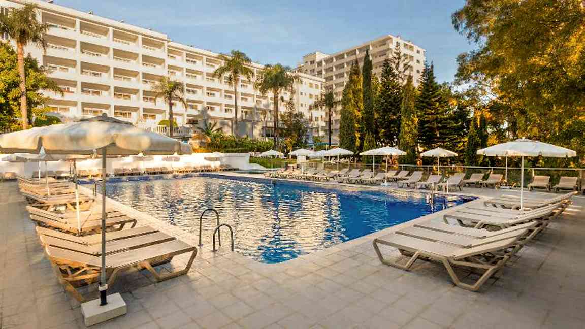Bild av en utomhuspool på ett hotell med omgivande solstolar och parasoller. (AI-genererad text)