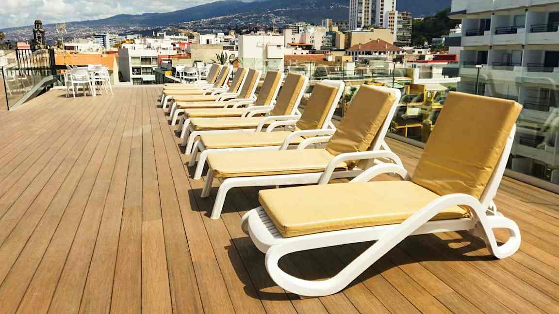 En takterrass med solstolar och utsikt över en stad och omgivande berg. (AI-genererad text)
