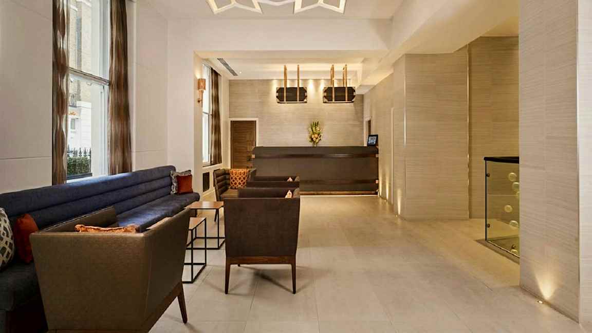 Ett modernt inrett lobbyutrymme med sittmöbler och receptionsdisk. (AI-genererad text)