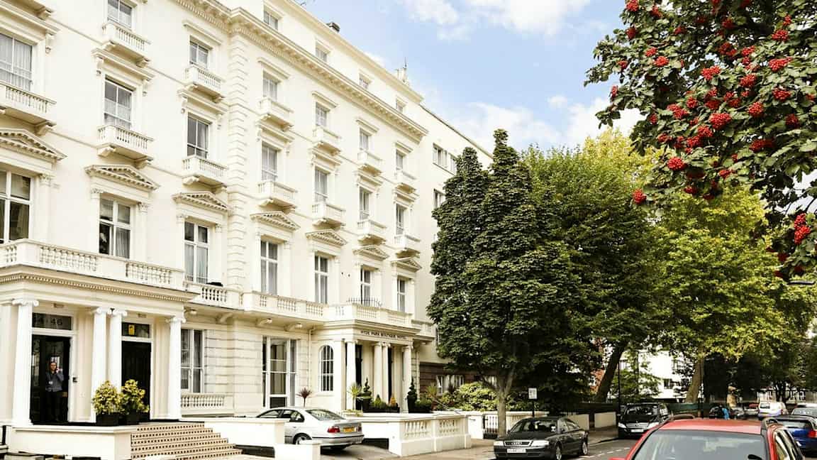 Flera vita byggnader med klassisk arkitektur längs en gata omgiven av träd. (AI-genererad text)