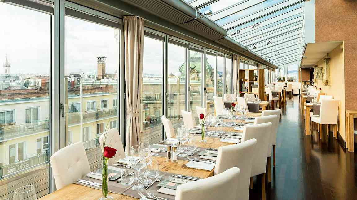 En ljus restaurang med glasväggar och tak, borden är dukade med vita stolar och en ros på varje bord. (AI-genererad text)