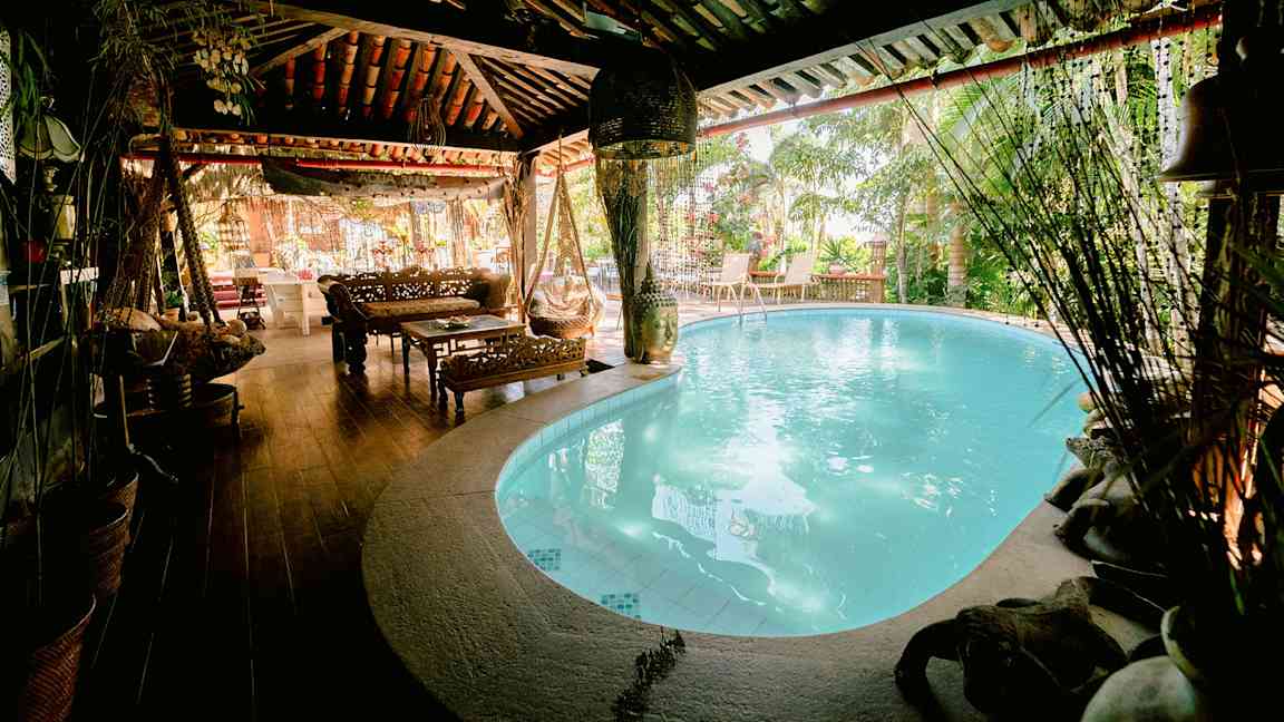 Ett mysigt utrymme med en pool inomhus, möbler i trä och växter runtom. (AI-genererad text)