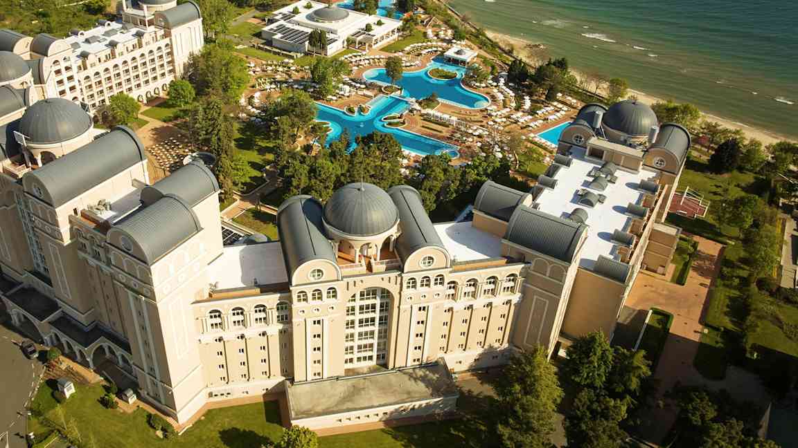 Vy från ovan av ett hotellkomplex med pooler och strand. (AI-genererad text)