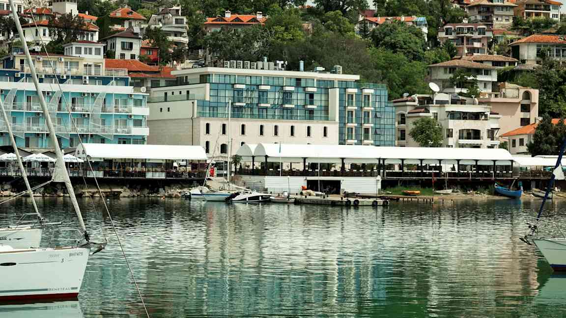 Bild av en hamn med båtar och byggnader i bakgrunden. (AI-genererad text)