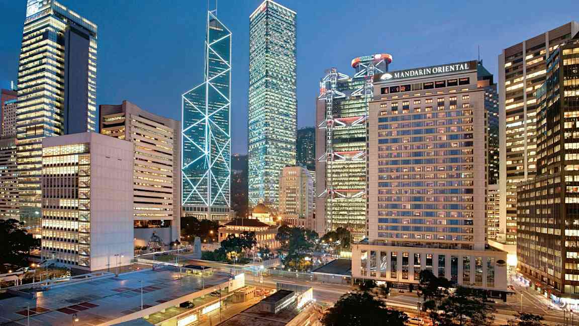 Stadsvy med höga byggnader upplysta i kvällsljus. (AI-genererad text)