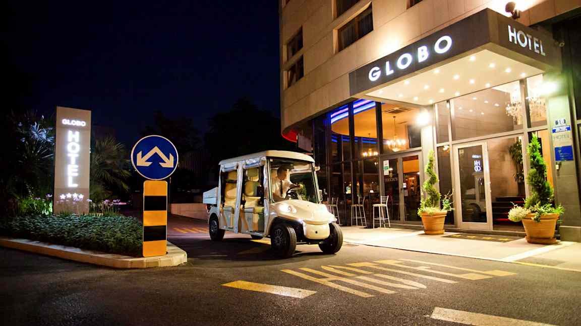 Ett hotell sett på natten med namnet Globo, en elbil står parkerad framför ingången. (AI-genererad text)