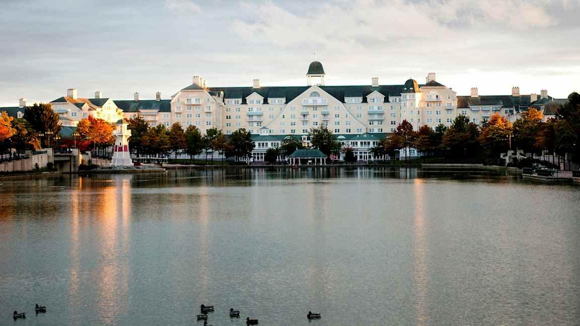 Hotellbyggnad vid en sjö med en liten fyr. (AI-genererad text)