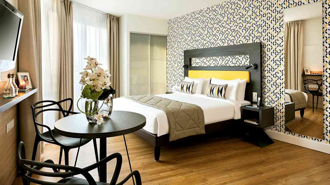 Ett modernt hotellrum med en dubbelsäng, färgglad tapet, och sittgrupp. (AI-genererad text)