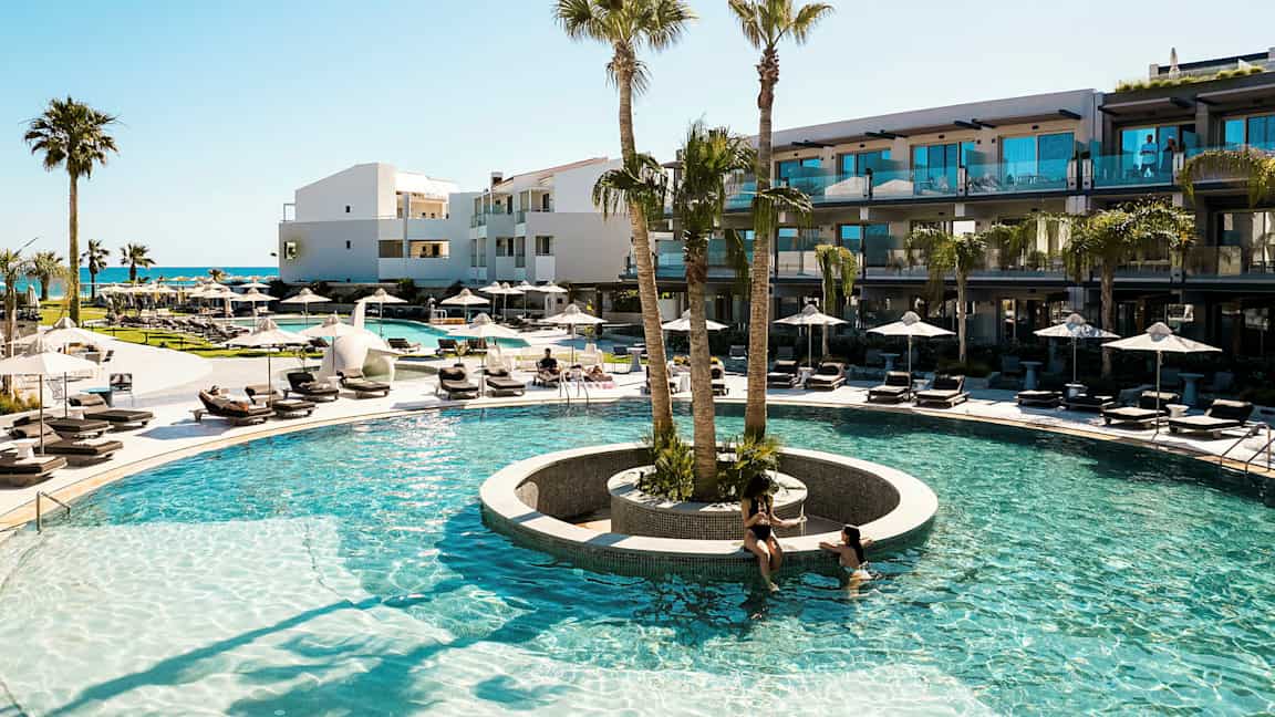 En utomhuspool med omgivande solstolar och palmer vid ett modernt hotell. (AI-genererad text)