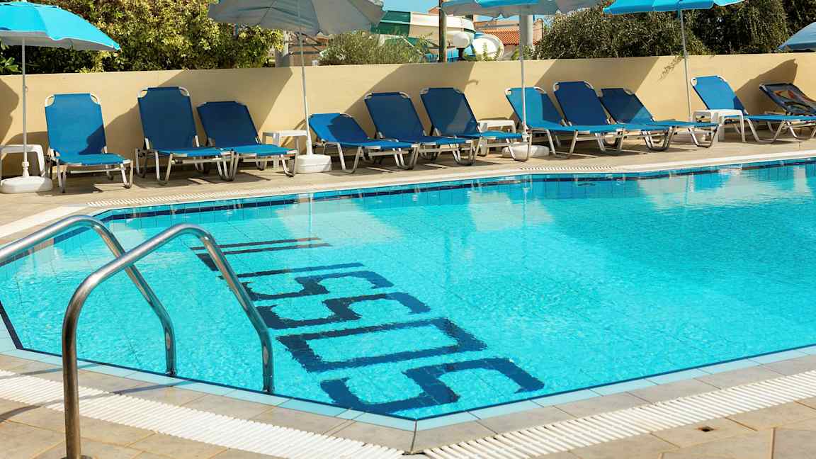En utomhuspool med blå solstolar och parasoller vid kanten. (AI-genererad text)