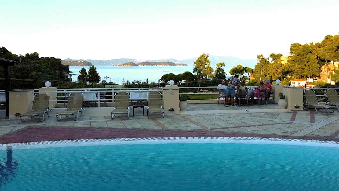 Utsikt från en poolterrass med solstolar, med hav och öar i bakgrunden. (AI-genererad text)
