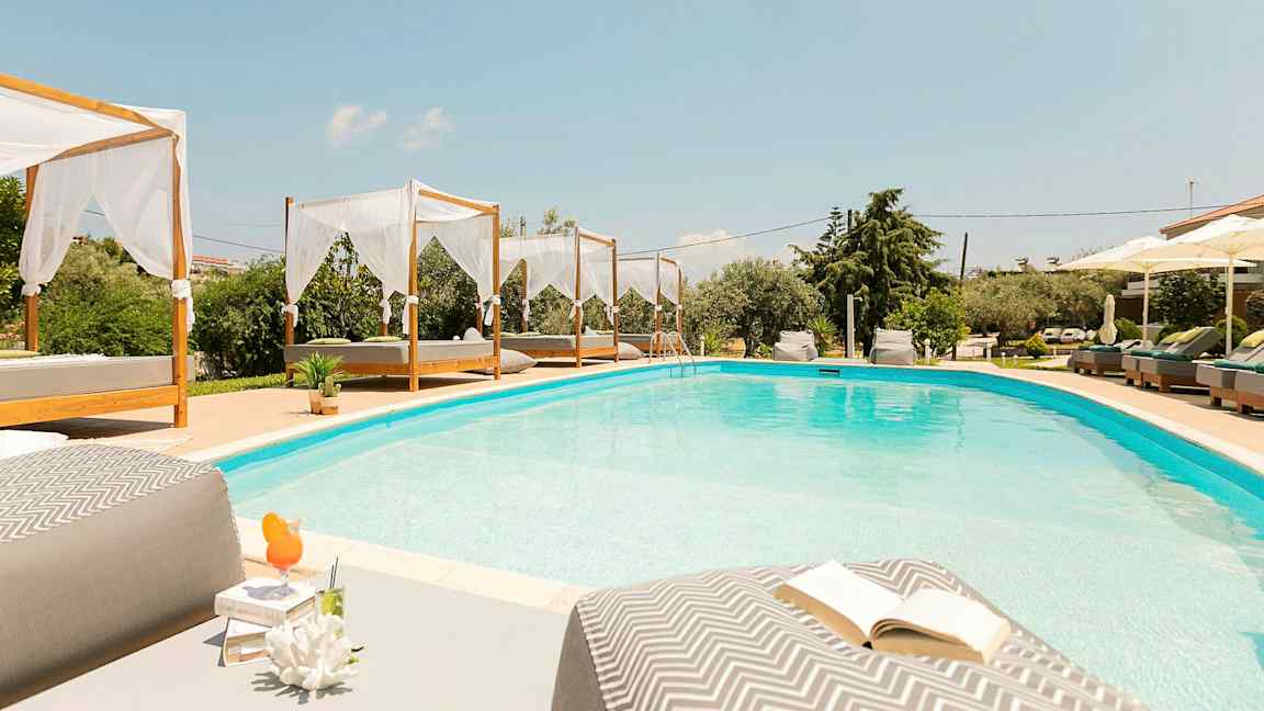 En swimmingpool med bäddar och parasoller runt omkring. (AI-genererad text)