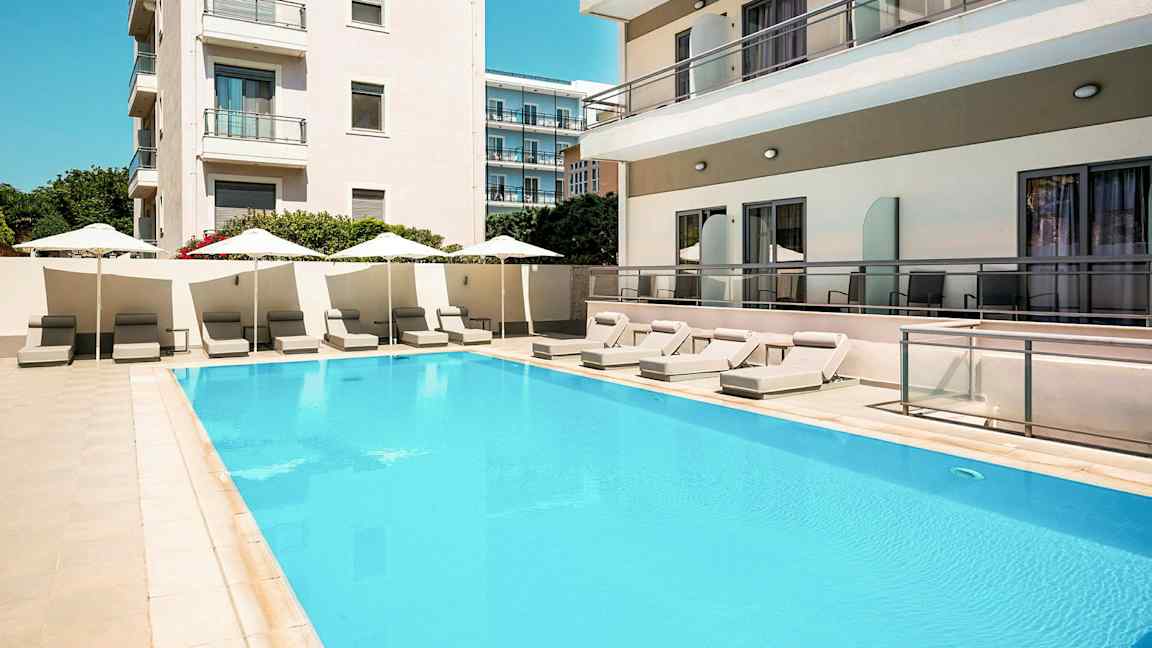 Simhall med solstolar och parasoller vid hotellbyggnader. (AI-genererad text)