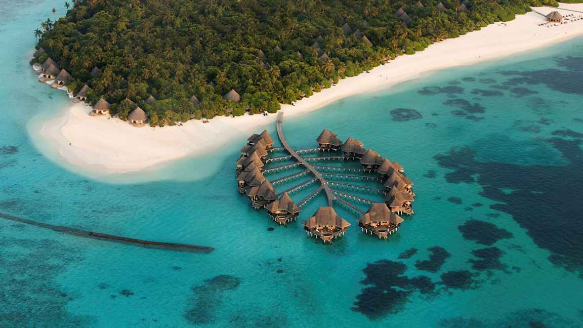 Flygfoto av tropisk ö med vita sandstränder och övervattensvillor. (AI-genererad text)