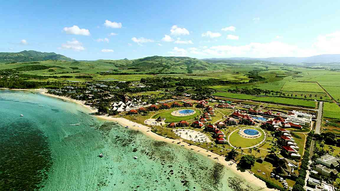 Flygfoto av en tropisk semesterort vid kusten, med pooler och gröna omgivningar. (AI-genererad text)