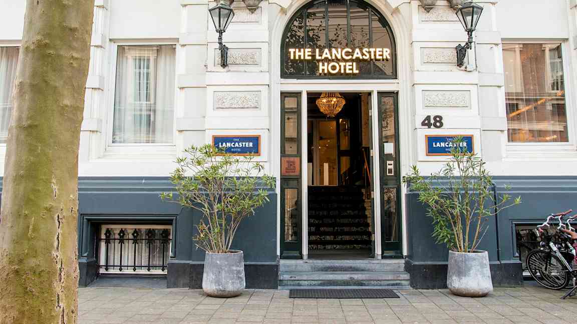 Entré till ett hotell med skylten 'The Lancaster Hotel' ovanför dörren. (AI-genererad text)