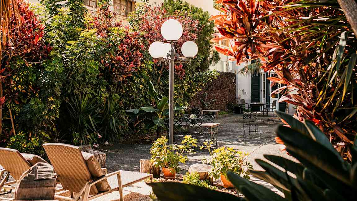 En solig innergård med trädgårdsmöbler och grönska. (AI-genererad text)