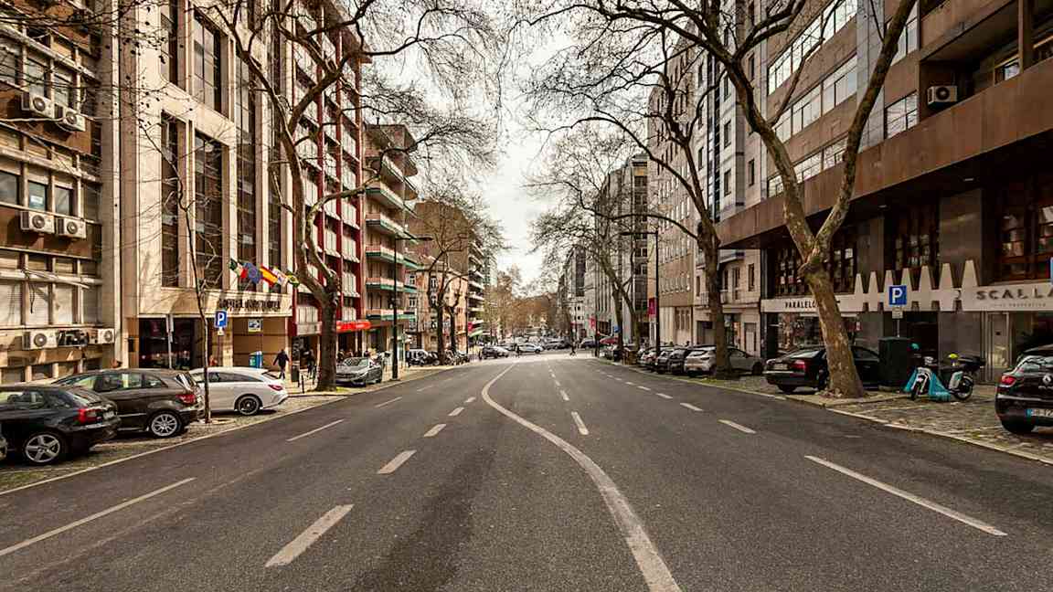 En bild av en tom stadsgata kantad av byggnader och träd. (AI-genererad text)