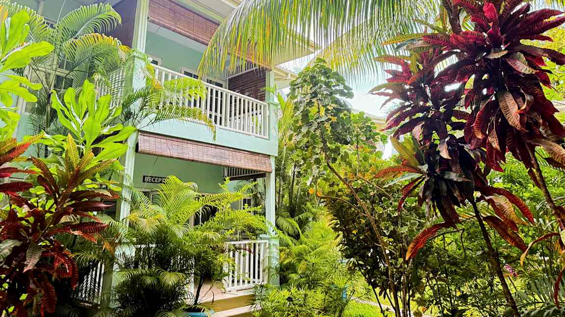 En byggnad med balkonger omgiven av frodig tropisk växtlighet. (AI-genererad text)