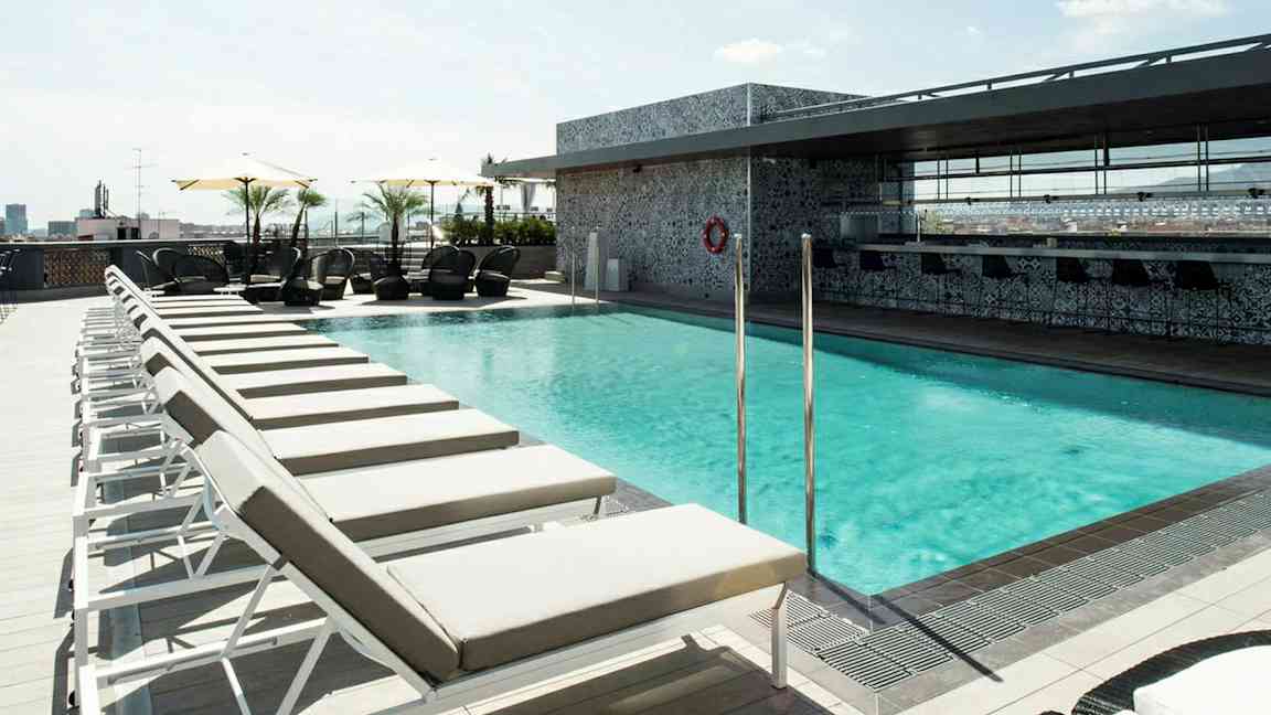 Bild av en solig takterrass med en pool omgiven av solstolar och parasoll. (AI-genererad text)