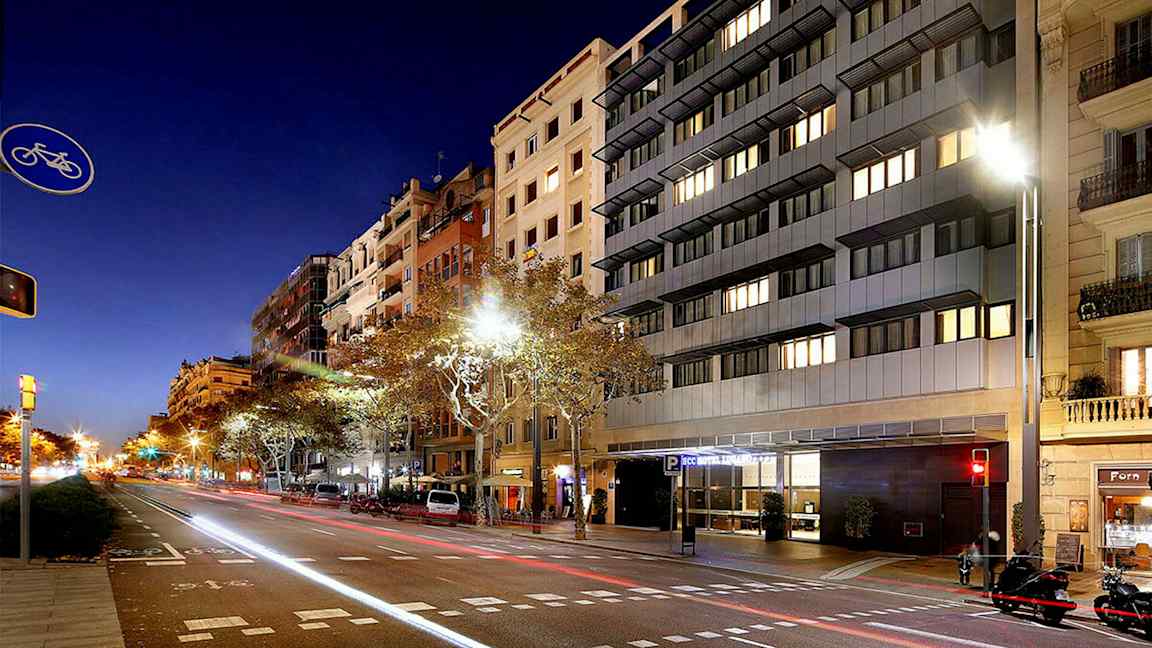 En gata i stadsmiljö på natten, med höga byggnader och bilar längs vägen. (AI-genererad text)