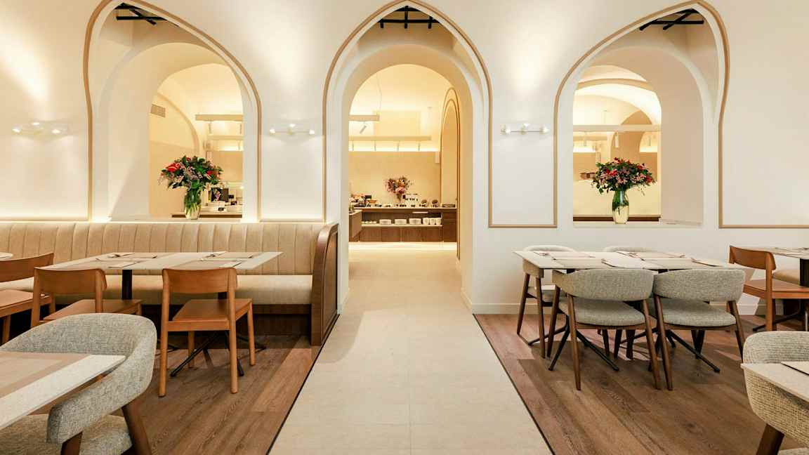 En elegant restaurang med bågformade fönster, trästolar och bord samt blomsterdekorationer. (AI-genererad text)