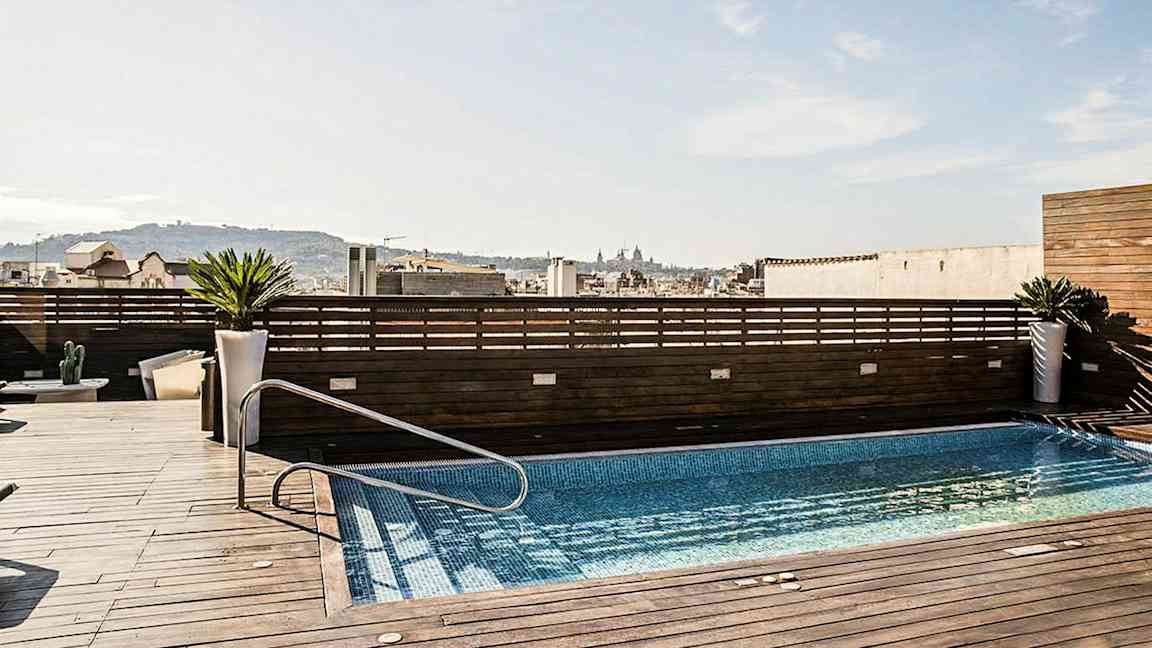 En takterrass med en pool, omgiven av träpaneler och med utsikt över en stad. (AI-genererad text)