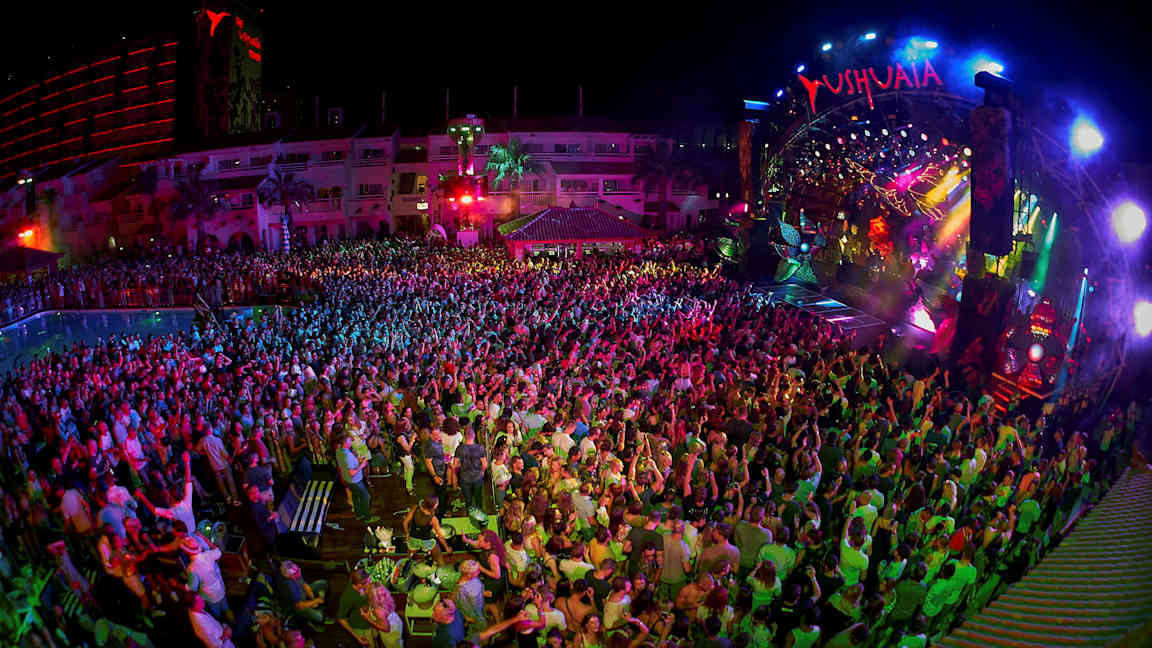 En nattklubb med ett publikhav framför en färgglatt lysande scen. (AI-genererad text)