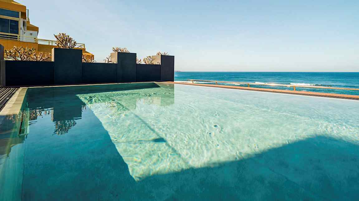 En infinitypool med utsikt över havet under en klar himmel. (AI-genererad text)