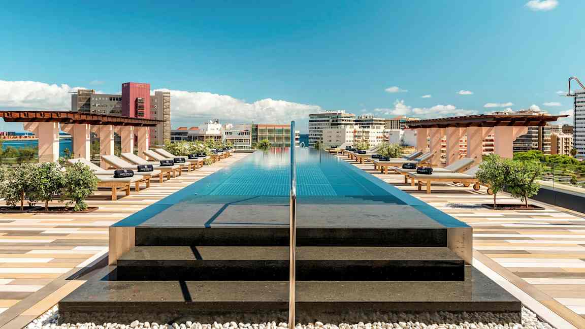 En takpool med solstolar och utsikt över staden under blå himmel. (AI-genererad text)