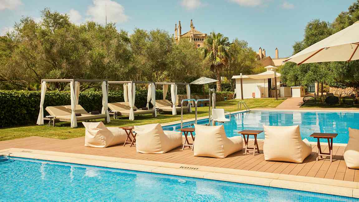 Utomhuspool med solstolar och parasoll, omgiven av grönska. (AI-genererad text)