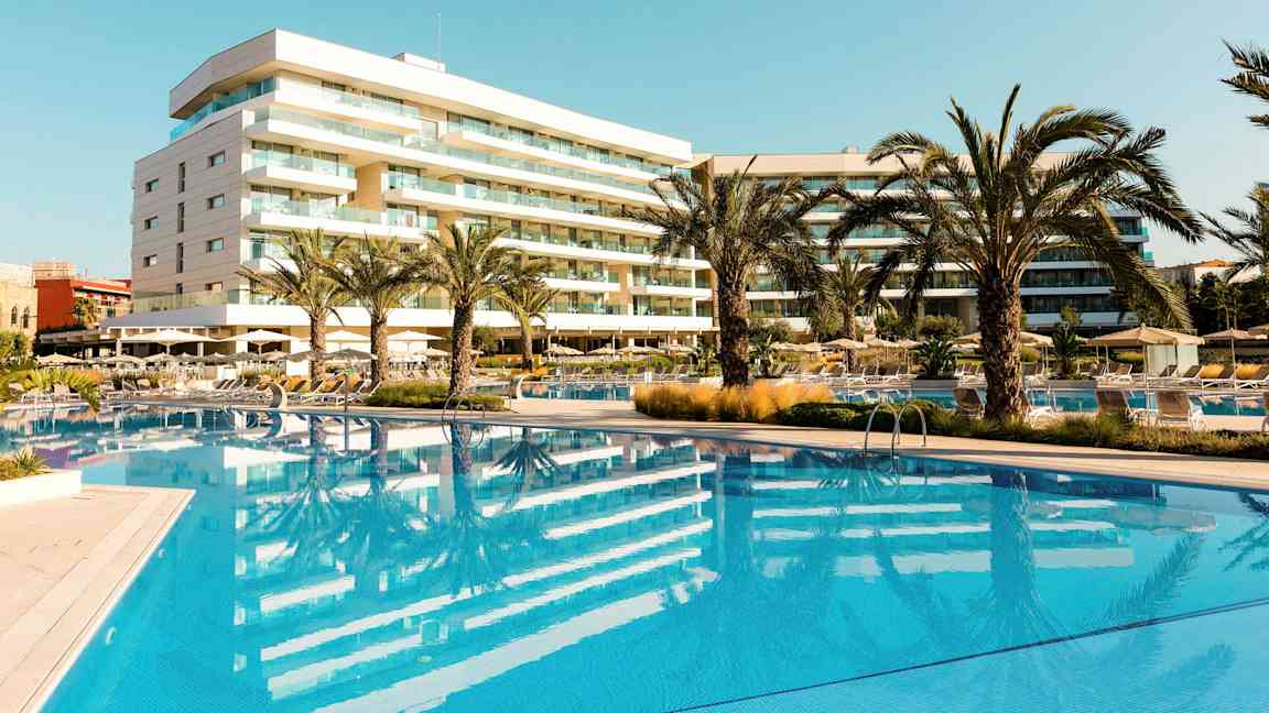 Hotell med pool och palmer i ett soligt område. (AI-genererad text)