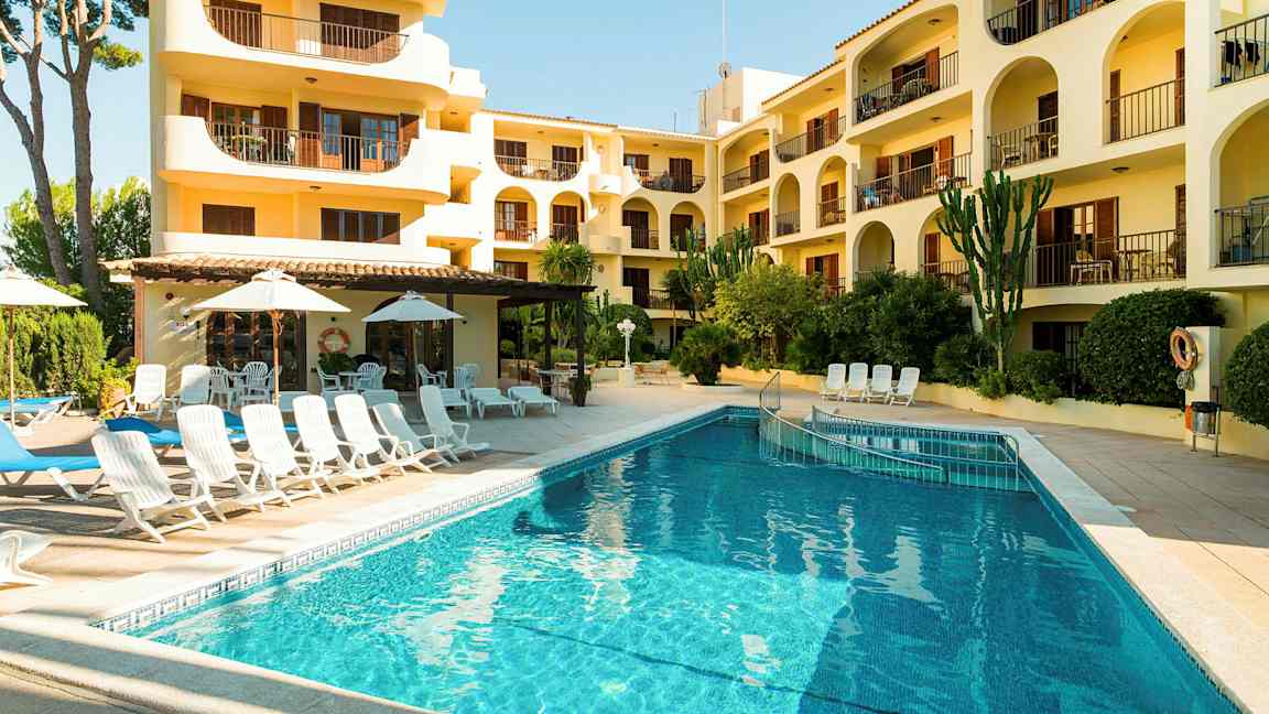 Ett hotell med balkonger och en pool bredvid solstolar och parasoller. (AI-genererad text)