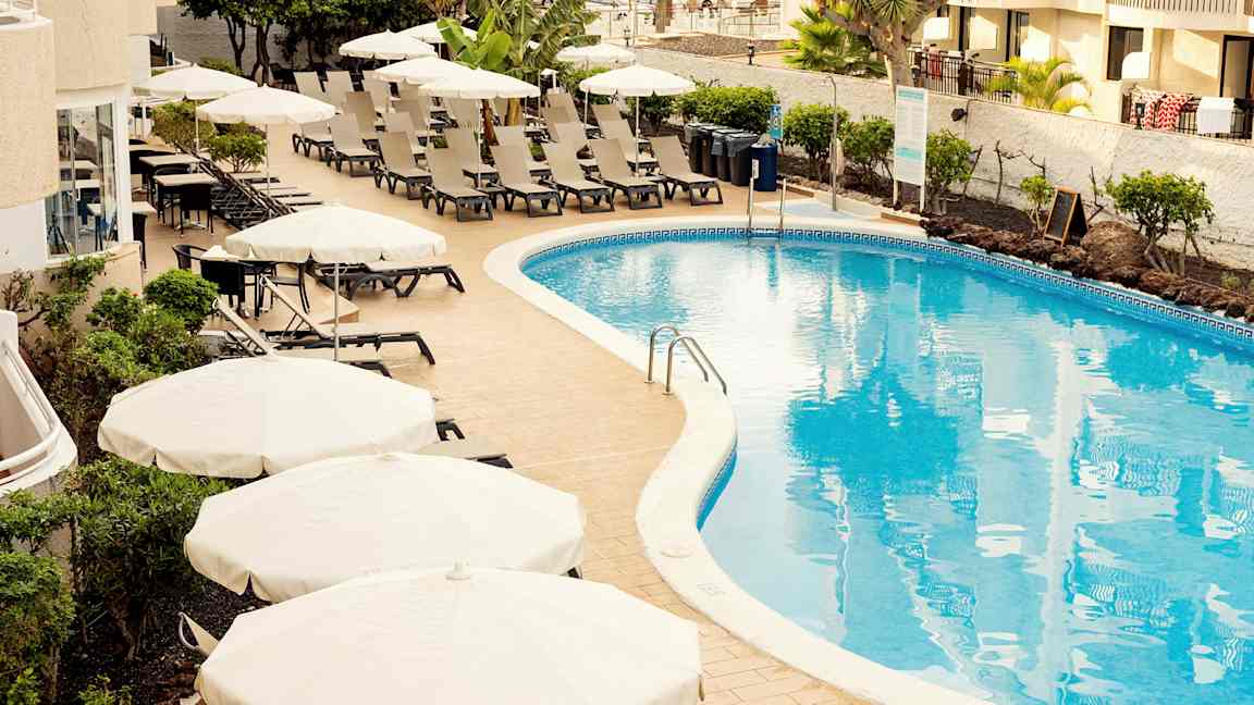 Poolområde med solstolar och parasoller vid ett hotell. (AI-genererad text)